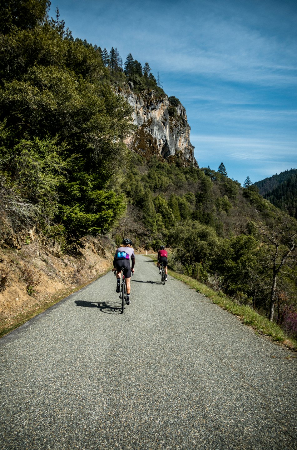 Due ciclisti percorrono in bicicletta una strada di montagna tortuosa.